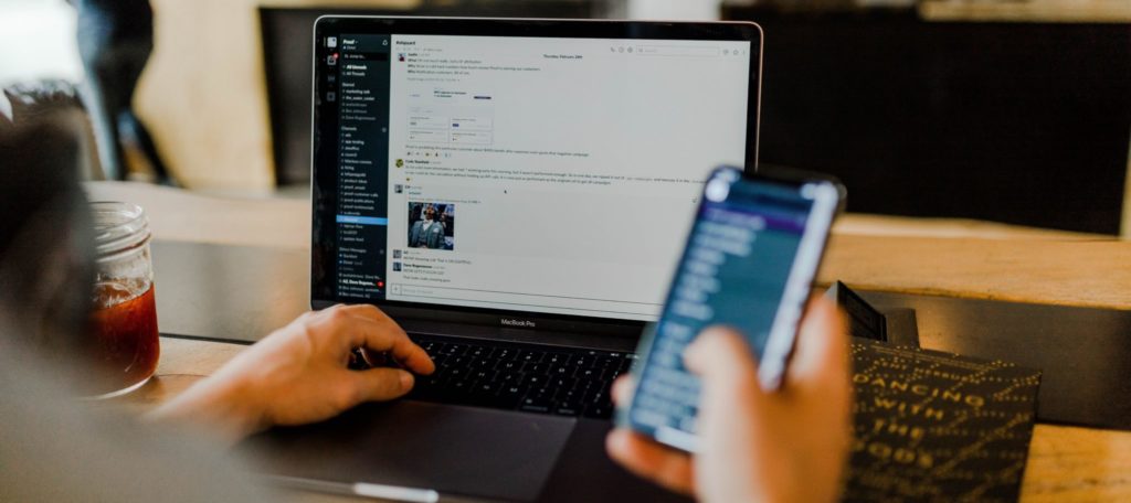 Image illustrating a person affected by California AB5 shows a hand holding a phone and someone looking at a computer screen.